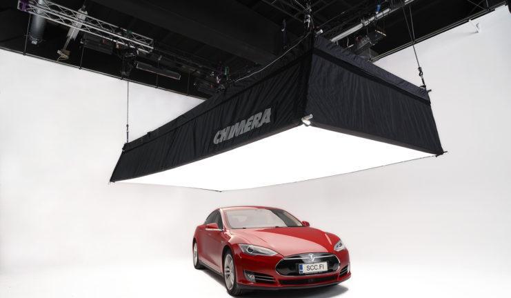 Professional film studio set with an all white background, Chimera lighting and a red Tesla.